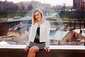 Portrait of cute girl smiling to camera in city on bulding background in sunny day.