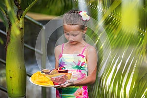 Portrait of a cute girl in the tropics. Girl holding a plate with exotic fruits