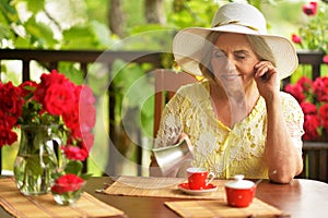 Portrait of cute happy aged woman drinking coffee