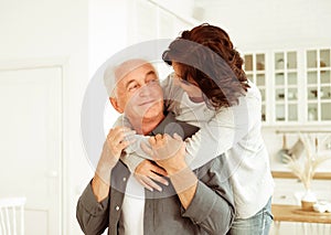 Portrait of cute happy Caucasian couple of retired husband and wife hugging indoors.