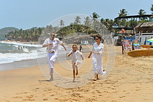 Portrait of cute happy family running on sandy beach