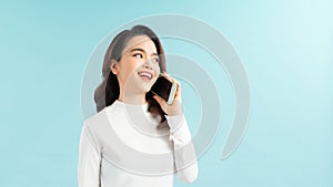 Portrait of a cute happy girl in dress talking on mobile phone and laughing isolated over blue background