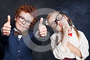 Portrait of cute happy kids in school uniform. Little boy and girl holding thumb up, thinking and smiling