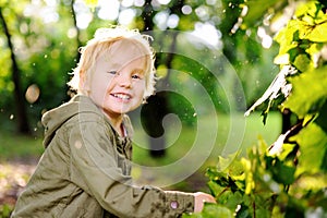 Portrait of cute happy little boy having fun in summer park after rain