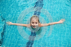 Portrait of cute happy little girl having fun in swimming pool.  Kids sport on family summer vacation. Active healthy holiday