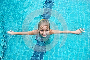 Portrait of cute happy little girl having fun in swimming pool.  Kids sport on family summer vacation. Active healthy holiday