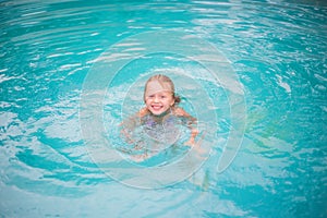 Portrait of cute happy little girl having fun in swimming pool. Kids sport on family summer vacation. Active healthy holiday