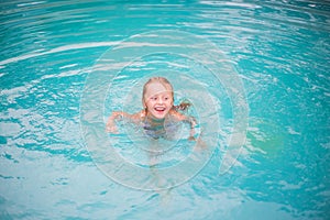 Portrait of cute happy little girl having fun in swimming pool. Kids sport on family summer vacation. Active healthy holiday