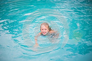 Portrait of cute happy little girl having fun in swimming pool. Kids sport on family summer vacation. Active healthy holiday