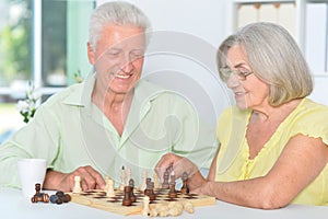 Portrait of cute happy senior couple playing chess together