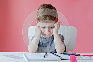 Portrait of cute kid boy at home making homework. Little concentrated child writing with colorful pencil, indoors. Elementary