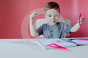 Portrait of cute kid boy at home making homework. Little concentrated child writing with colorful pencil, indoors. Elementary