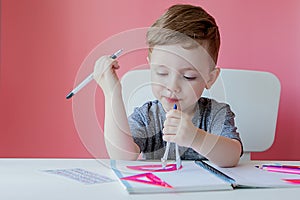 Portrait of cute kid boy at home making homework. Little concentrated child writing with colorful pencil, indoors. Elementary