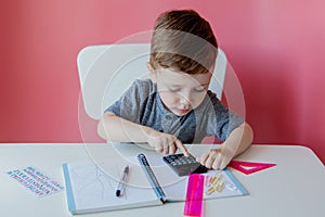 Portrait of cute kid boy at home making homework. Little concentrated child writing with colorful pencil, indoors. Elementary