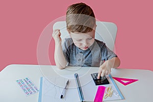 Portrait of cute kid boy at home making homework. Little concentrated child writing with colorful pencil, indoors. Elementary