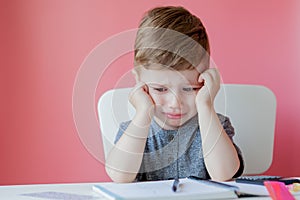 Portrait of cute kid boy at home making homework. Little concentrated child writing with colorful pencil, indoors. Elementary