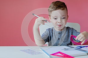 Portrait of cute kid boy at home making homework. Little concentrated child writing with colorful pencil, indoors. Elementary