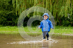 Portrait of cute kid boy playing with handmade ship. kindergarten boy sailing a toy boat by the waters` edge in the park