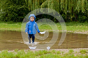 Portrait of cute kid boy playing with handmade ship. kindergarten boy sailing a toy boat by the waters` edge in the park