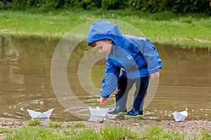 Portrait of cute kid boy playing with handmade ship. kindergarten boy sailing a toy boat by the waters` edge in the park