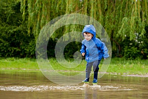 Portrait of cute kid boy playing with handmade ship. kindergarten boy sailing a toy boat by the waters` edge in the park