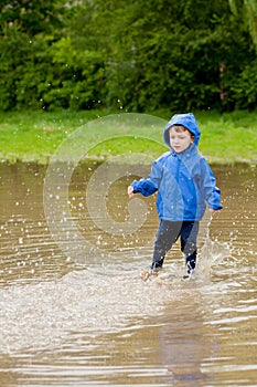 Portrait of cute kid boy playing with handmade ship. kindergarten boy sailing a toy boat by the waters` edge in the park