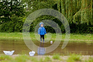 Portrait of cute kid boy playing with handmade ship. kindergarten boy sailing a toy boat by the waters` edge in the park