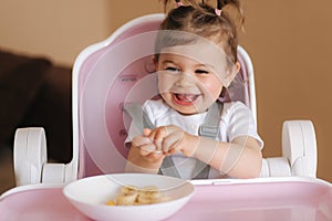 Portrait of cute laughing little girl in hight chair