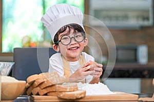 Portrait cute little Asian happiness boy interested in baking bakery with funny in home kitchen. People lifestyles and Family.