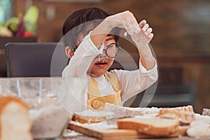 Portrait cute little Asian happiness boy interested in baking bakery with funny in home kitchen. People lifestyles and Family.