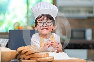 Portrait cute little Asian happy boy interested in cooking funny in home kitchen. People lifestyles and Family. Homemade food and