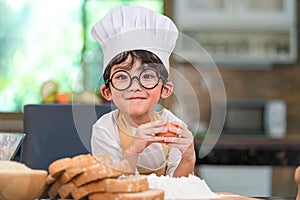 Portrait cute little Asian happy boy interested in cooking funny in home kitchen. People lifestyles and Family. Homemade food and