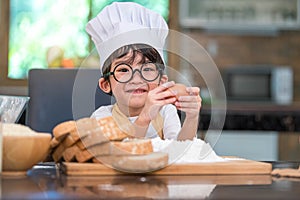 Portrait cute little Asian happy boy interested in cooking funny in home kitchen. People lifestyles and Family. Homemade food and