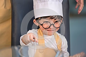 Portrait cute little Asian happy boy interested in cooking with mother funny in home kitchen. People lifestyles and Family.