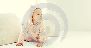 Portrait of cute little baby in bathrobe in white room at home near window