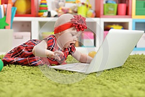 Cute little baby girl with laptop on floor