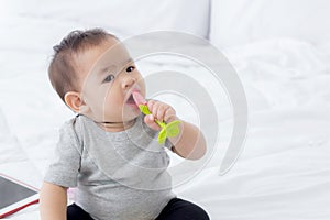 Portrait of cute little baby girl sitting with cozy on bed at bedroom, happiness of toddler.