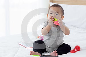 Portrait of cute little baby girl sitting with cozy on bed at bedroom, happiness of toddler.