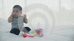 Portrait of cute little baby girl sitting with cozy on bed at bedroom, happiness of toddler.