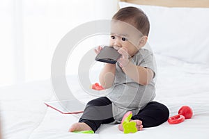 Portrait of cute little baby girl sitting with cozy on bed at bedroom, happiness of toddler.