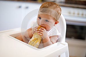 Portrait of cute little baby girl sitting in high chair and waiting for feeding