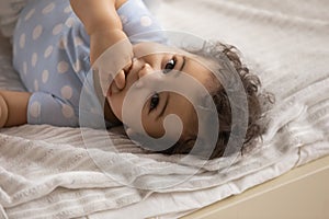 Portrait of cute little biracial baby lying in cozy bed