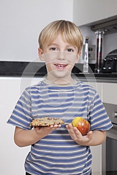 Portrait of cute little boy choosing between apple and chocolate chip cookie