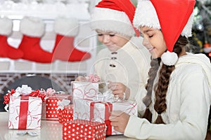 Cute little boy and girl with gifts for Christmas at home