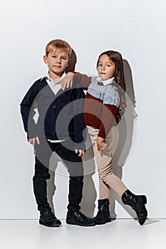 The portrait of cute little boy and girl in stylish jeans clothes looking at camera at studio