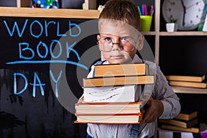 Portrait of cute little boy holding book in classroom. Happy International World Book Day