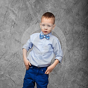 Portrait of a cute little boy in jeans, blue shirt and bow tie o