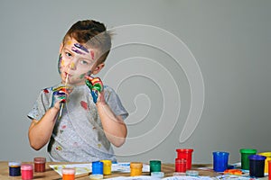 Portrait of a cute little boy messily playing with paints