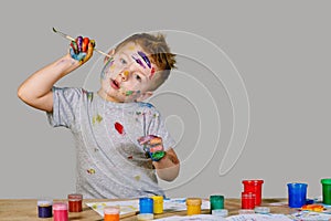 Portrait of a cute little boy messily playing with paints