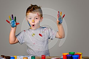 Portrait of a cute little boy messily playing with paints